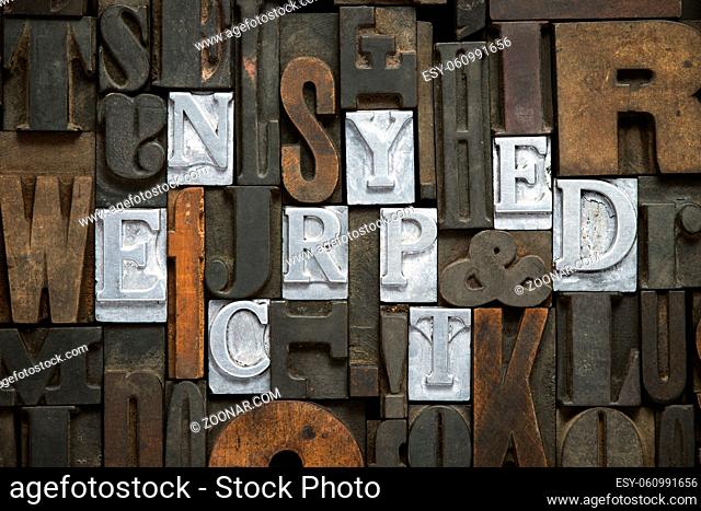 encrypted concept made from metallic letterpress blocks in mixed wooden letters