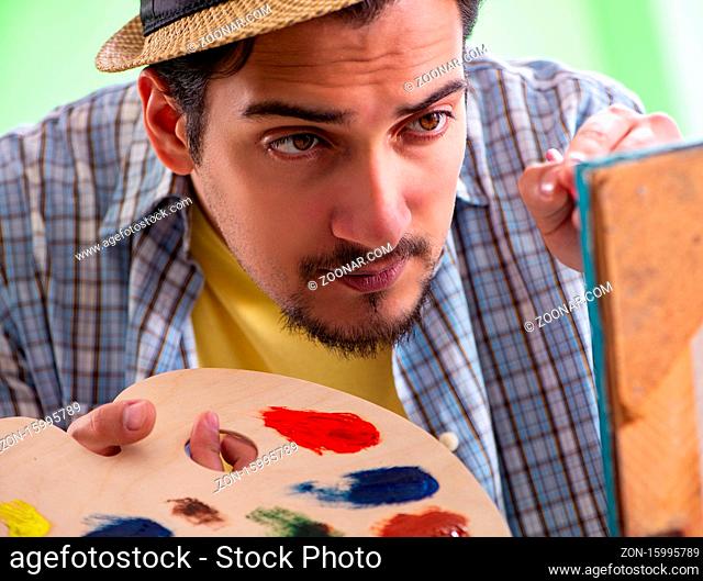 The young male artist working on new painting in his studio