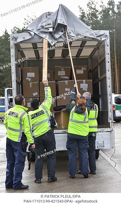Police officers lifting the tarpaulin of the cargo section of a Polish van at a rest stop along the A12 highway near Briesen, Germany, 12 October 2017