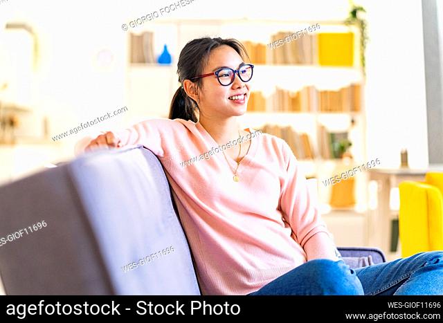 Thoughtful woman sitting on sofa at home