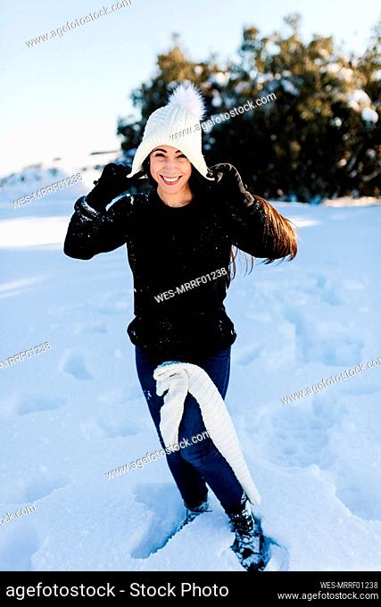 Smiling woman wearing knit hat enjoying in snow