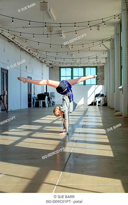 Teenage girl doing handstand and splits in dance studio