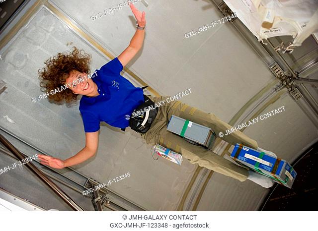 NASA astronaut Dorothy Metcalf-Lindenburger, STS-131 mission specialist, holds stowage containers with her legs while floating freely in the Leonardo...