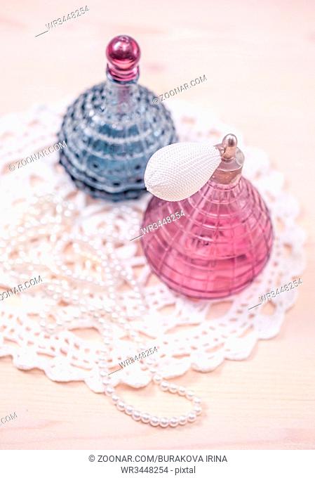 Two glass bottles of female perfume on a white background. Pink toning