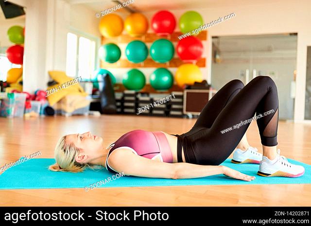 Junge Frau liegt auf dem Rücken und macht eine Yoga Übung zur Entspannung