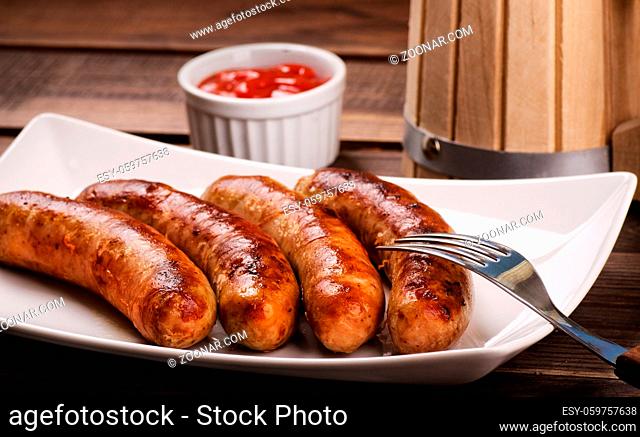 Grilled sausages with beer mug on a wooden table