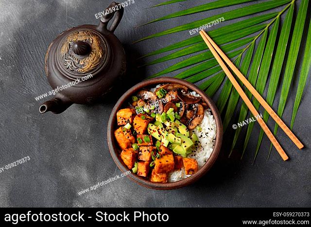 Sweet, spicy , crispy and fried Tofu in teriyaki sauce served in a bowl with avocado, fried mushrooms, sesame seeds and rice
