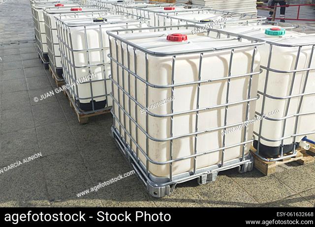 Lots of cube water tanks. 1000 litres containers piled outdoors
