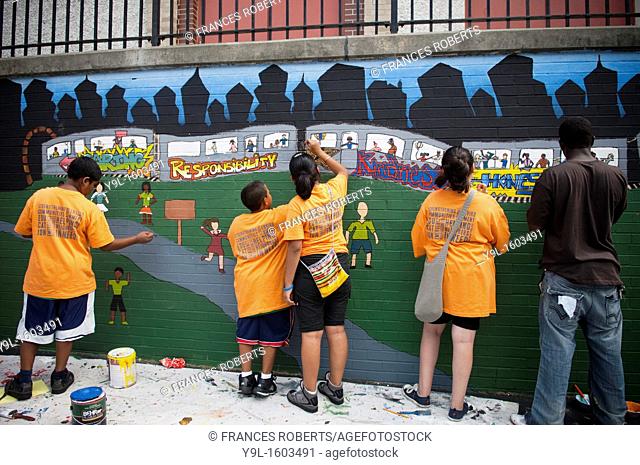 Volunteers and students paint a mural against bullying at a middle school in the Richmond Hill neighborhood in the borough of Queens in New York