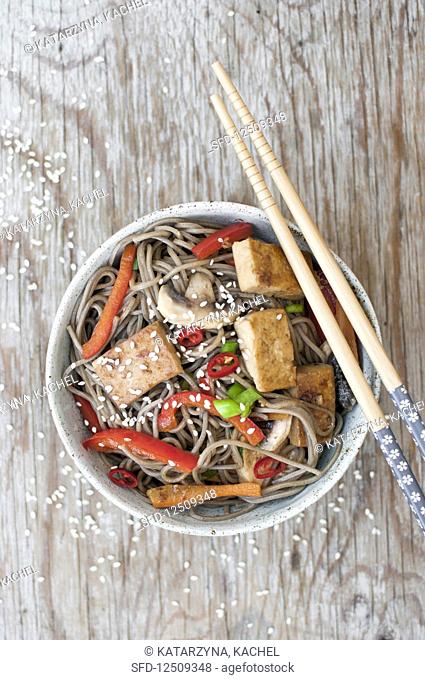 Yaki soba with tofu, bell pepper and mushrooms, sprinkled with green onion, sesame and fresh chili (glutenfree)