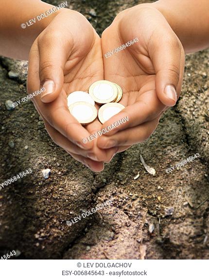 poverty, starvation, ecology and charity concept - closeup of female hands holding euro coins over ground background