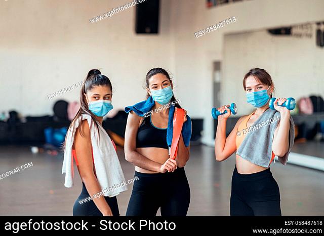 Three happy smiling positive girls after training in the gym. There are looking at camera. Horizontal