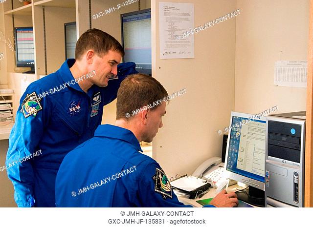 Astronauts Stanley G. Love (seated) and Rex J. Walheim, STS-122 mission specialists, use a computer in the check-out facility at Ellington Field near Johnson...