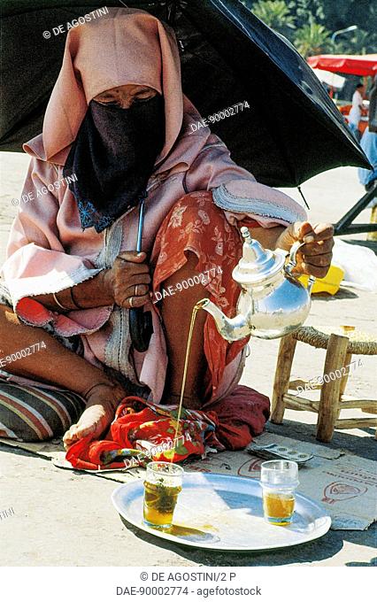 Woman pouring mint tea, Djemaa el Fna square at sunset, medina of Marrakech (UNESCO World Heritage List, 1985), Morocco