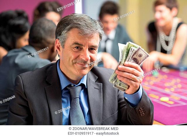 Man holding up money at roulette table