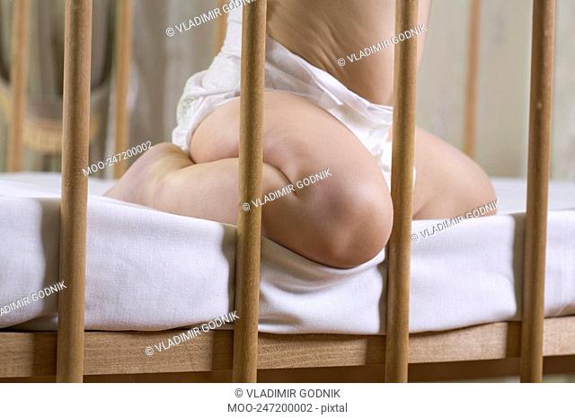 INfant child kneeling in cot