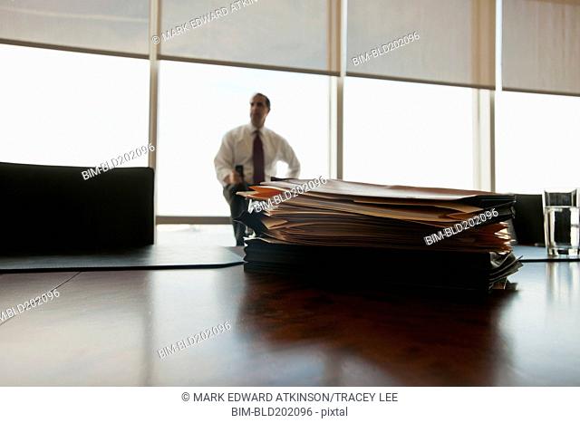 Caucasian businessman sitting behind stack of folders
