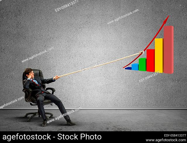 Young man in chair and growing graph presenting growth progress
