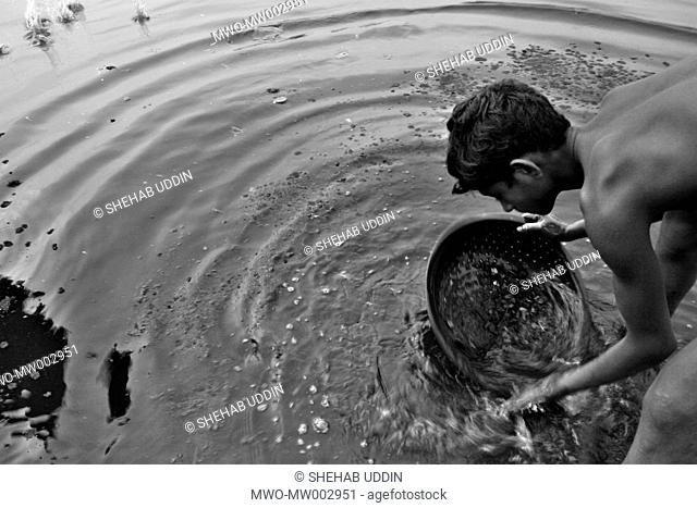 Waste from the small factories are regularly dumped on the banks of the river Buriganga polluting the waters A small child grabs this waste