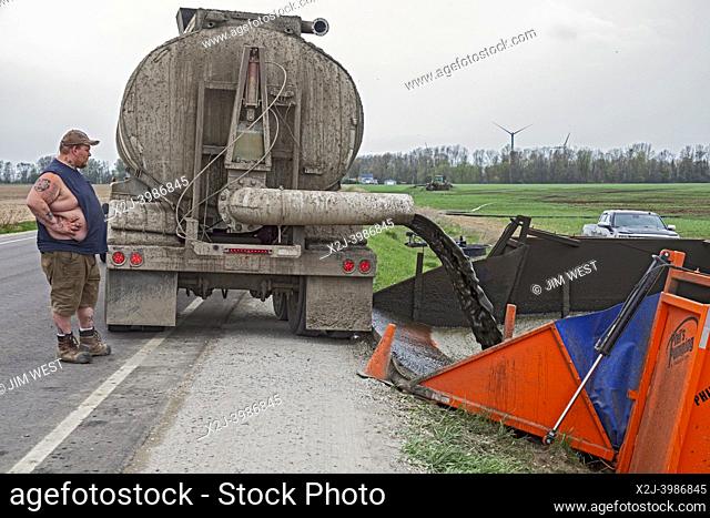 Elkton, Michigan - Cow manure is unloaded from a tank truck and pumped to a distant tractor which spreads it onto a farm field as a fertilizer