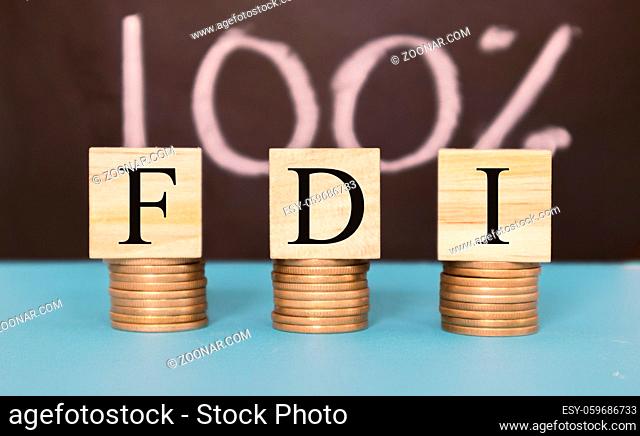 Finance Concept with Stack of Coins - 100 percent FDI or Foreign Direct Investment on wooden blocks