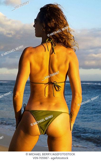 Model wearing green bikini on beach from back