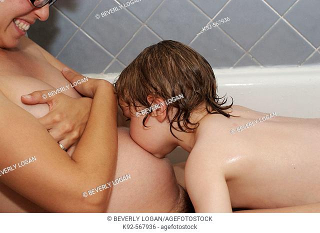 Three year old boy and pregnant mother taking a bath