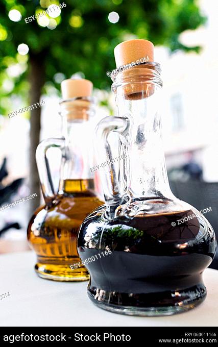 Bright yellow olive oil and black balsamic vinegar on the restaurant kitchen table. Two bottles foreground. Bottling of dressing
