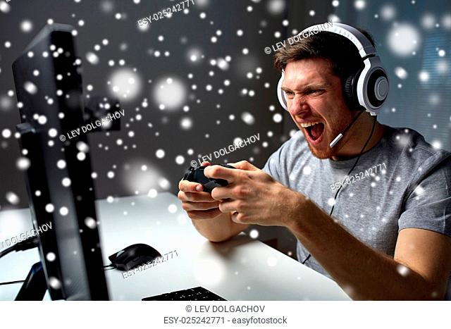 technology, gaming, entertainment, play and people concept - screaming young man in headset with controller gamepad playing computer game and streaming...