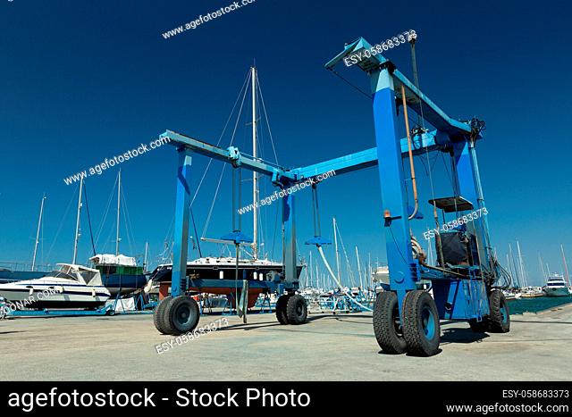 Blue lifting crane for elevating boat and maintenance machine at harbor dock
