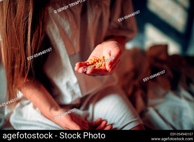 Young sick woman sitting on hospital bed with drugs in hand. Illness of female patient in clinic, health recovery and treatment