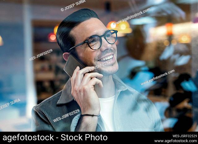 Smiling architect talking on smart phone in office