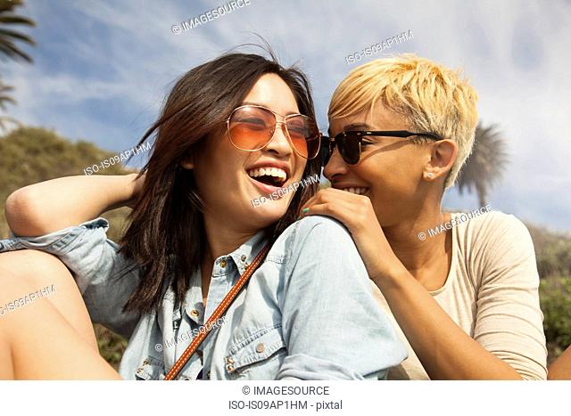 Two female friends, outdoors, laughing together