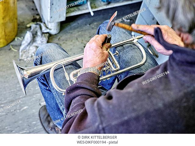 Instrument maker repairing trumpet in workshop