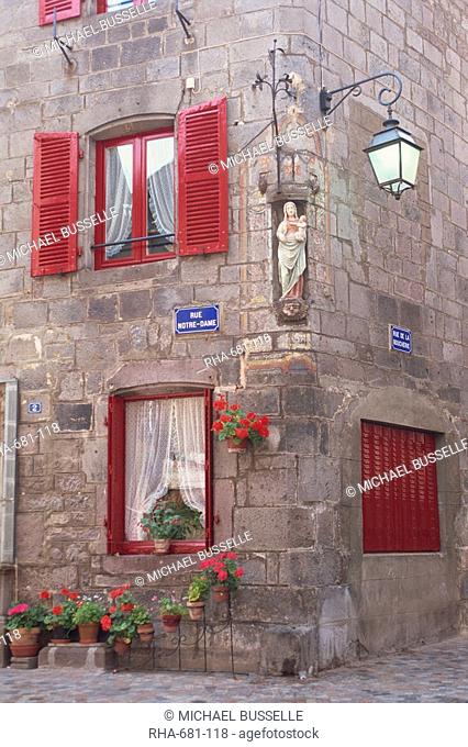 Statue of the Madonna and Child on a house with red shutters on a street corner in Besse en Chandesse, in the Auvergne, France, Europe