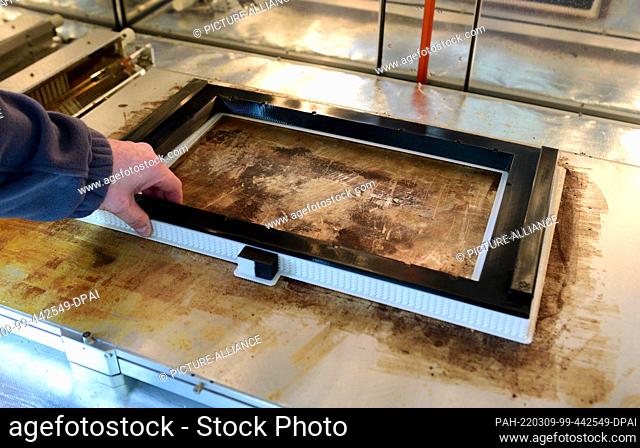 PRODUCTION - 24 February 2022, Schleswig-Holstein, Neumünster: An employee takes a frame for screens for an ICE train from a 3D printer at the Deutsche Bahn...