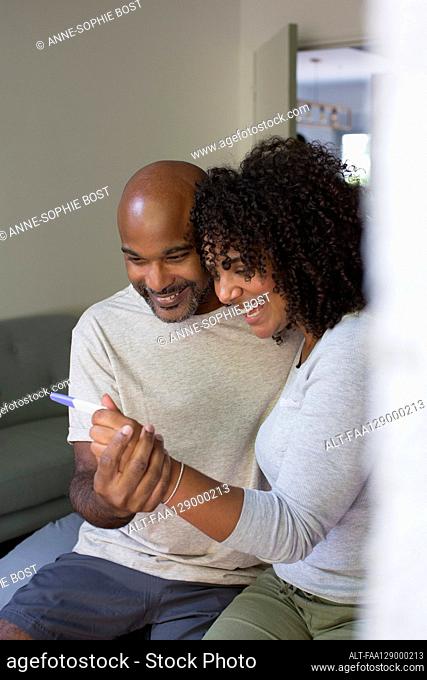 Happy couple holding pregnancy test kit