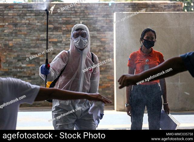 A worker disinfects a man entering the city hall amid the coronavirus pandemic, in Pasig City, Metro Manila, Philippines