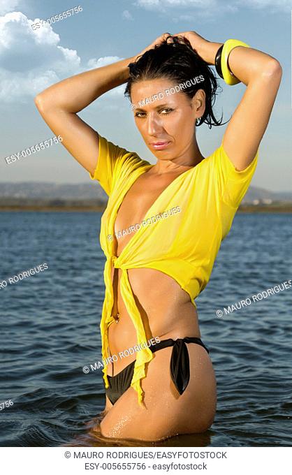 View of a beautiful woman in bikini in the beach, bathed by the sunny rays of Summer