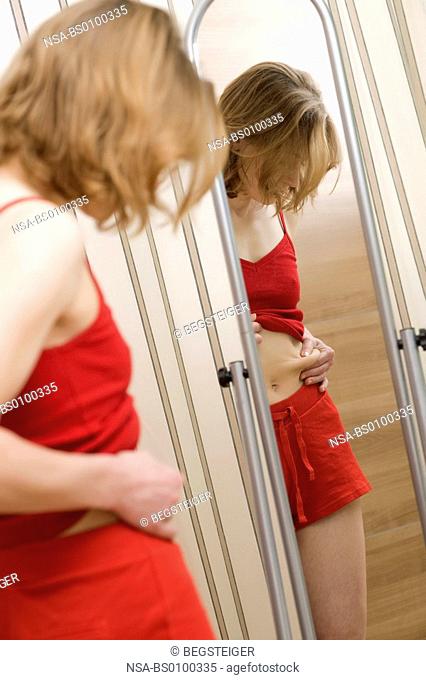 rank, young woman front of the mirror looking for belly of pork
