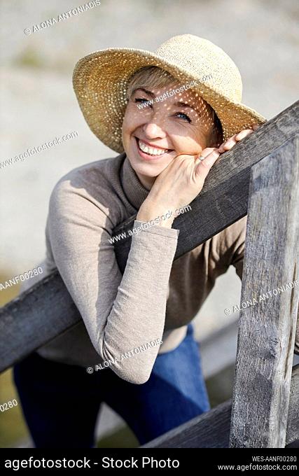 Happy mature woman leaning on railing