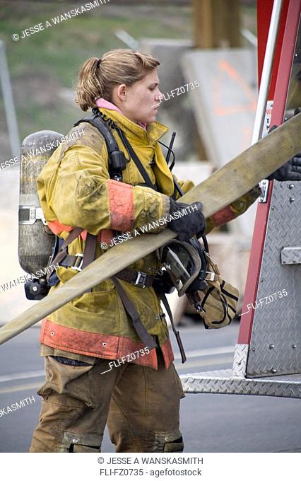 Female firefighter removing hose from fire truck, Spokane, Washington