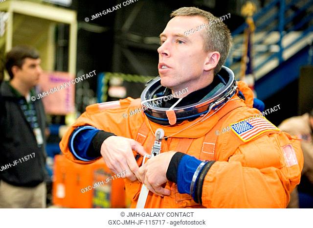 NASA astronaut Andrew Feustel, STS-134 mission specialist, dons a training version of his shuttle launch and entry suit in preparation for a training session in...