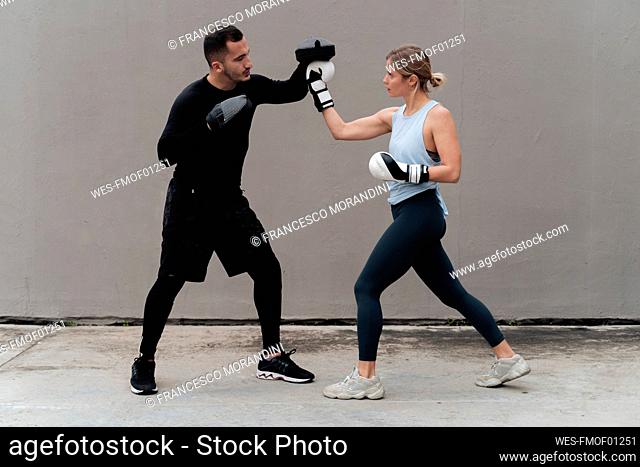 Couple practicing boxing while standing against wall
