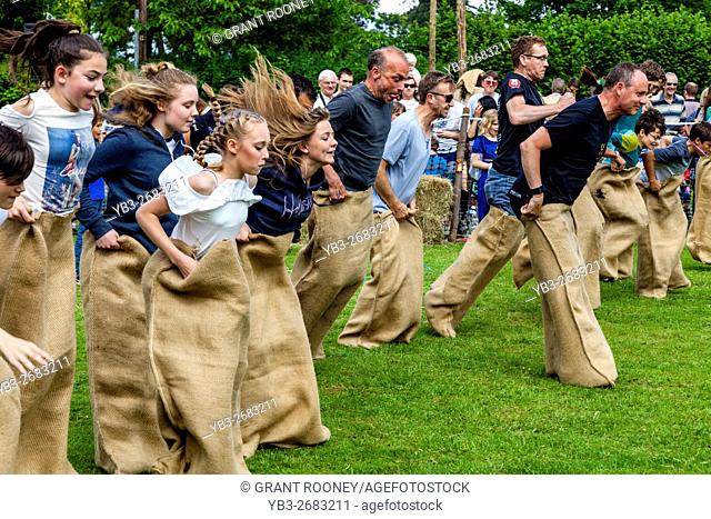 Teenagers and Adults Race In A Traditional Sack Race At The Medieval Fair Of Abinger, Surrey, UK