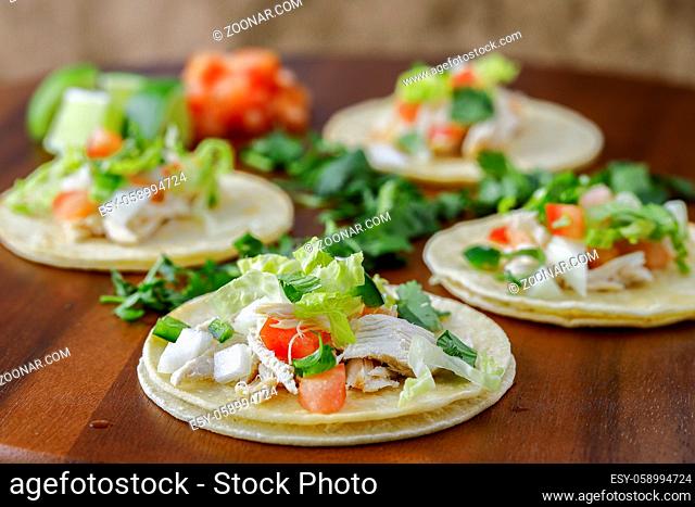 A close up photo of four street tacos displayed on a wooden board