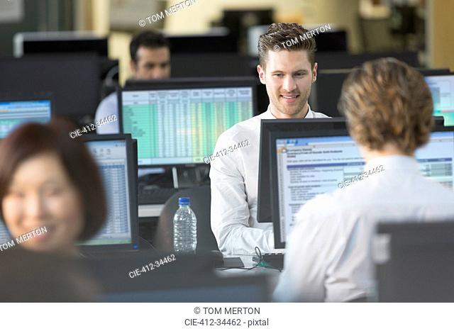 Businessmen working at computers in open plan office