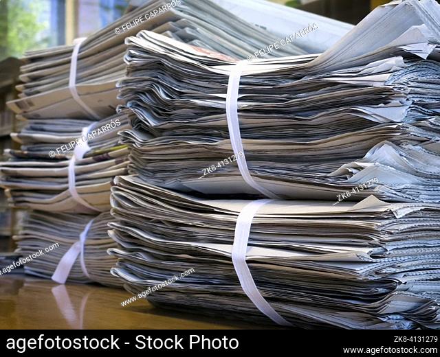 Newspapers stacked on top of a table