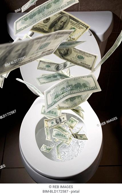 Dollar bills falling into toilet