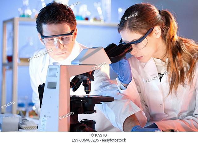 Attractive young scientist and her post doctoral supervisor working on a project in the forensic laboratory